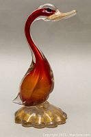 Side view of reddish amber Murano swan glass sculpture with clear base and gold flecks