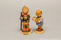 Pair of Western German GOEBEL hand-painted ceramic figurines, one boy with walking stick and one child holding toilet paper and flowers.