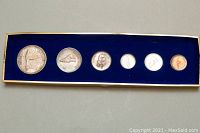 Six Canadian Centennial coins displayed in a row inside a blue velvet box with gold trim.