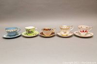 Front view of five teacup and saucer sets showing colors and detail
