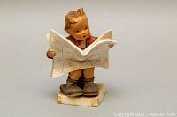 Front view of the Goebel figurine of a boy reading a newspaper, showing detailed hand-painted features.
