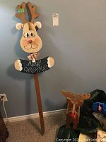 Photo of a tall wooden reindeer sign with a smiling face and 'Merry Christmas' chalkboard