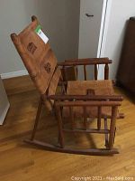 Side view of the wood framed rocking chair with leather seat and back depicting structural details and folding mechanism.