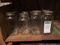 Front row of large Mason jars with metal lids, embossed branding visible, jars in lightly used condition.