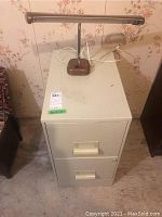 Photo of 2-drawer metal filing cabinet with retro fluorescent desk lamp on top, beige color, showing front and side views of cabinet and lamp