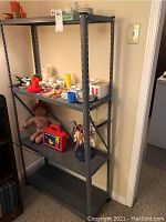 Gray metal shelving unit with assorted children's toys including doll, sewing kit, and toy case placed on shelves