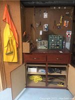 Yellow and orange raincoat hanging on the left side of pegboard with workbench and hardware organizers below.