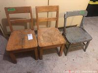 Three children's chairs side by side: two wooden chairs with ladder backs and one small metal chair painted gray. Chairs show heavy wear and need refinishing.