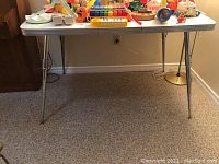 Front view of vintage retro kitchen table showing white laminate top with gold sparkles and chrome steel legs.