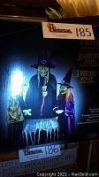 Box front showing three witches, with black and purple costumes around a cauldron, lit up with LED lights.