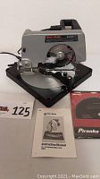 Front view of Black & Decker compound mitre saw with instruction manual and Piranha Pro saw blade box on table
