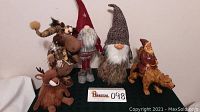 Full set of Christmas gnomes, moose, Santa, and reindeer displayed on a table against a white wall.
