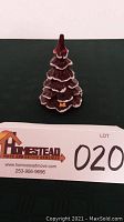 Front view of the red art glass Christmas tree on a black surface with a lot tag visible.