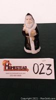 Handpainted Santa Claus figurine standing 8 inches tall with black coat, white trim, holding a list and sack.