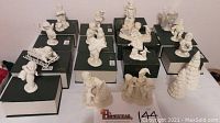 Full lot arranged on green and white boxes featuring 16 white porcelain Snowbabies figurines, winter and holiday themes.