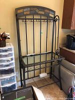 Front view of bakers stand showing glass top, hooks, slate tiles on upper arch, and lower metal rack shelf.