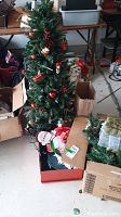 Artificial Christmas tree set up with some ornaments and surrounding boxes of decorations.