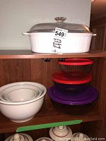 Three Pyrex glass bowls with colorful lids stacked next to ceramic mixing bowls