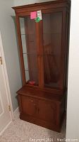 Full view of wooden curio cabinet with glass upper doors and wooden lower doors.