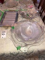 Photo showing five clear glass serving bowls with decorative wavy edges and textured patterns, a metal serving tray with removable plastic trays placed on a table.