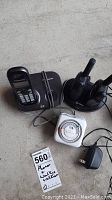 Clear image showing all items in the lot: Panasonic cordless phone with base, pair of walkie talkies on charging base, and white international outlet timer with attached power adapter.