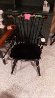 Front view of black wooden rocking chair with floral design on top backrest rail and curved rockers.