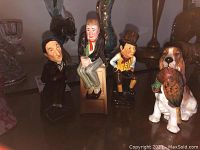 Four ceramic figurines: three Royal Doulton characters and one Gibsons dog figurine with a pheasant in mouth, all arranged on a display surface.