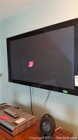 Front view of Pioneer flat-screen TV mounted on wall, with visible Pioneer logo on bezel. TV screen has a small pink sticky note.