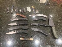 Overview of all folding knives, fixed blades and accessories on countertop