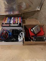Boxes containing many wired headphones, DVDs, and electronic devices including a tablet and Fisher Price item.