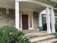 Front porch view showing two planter pots, teal cylindrical and small decorative pot