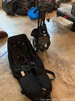 Wide angle showing both golf travel bag and Speed Cart push cart on the floor in a storage area.