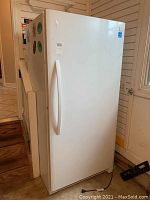 Full front and side view of the white Kenmore upright freezer, showing door handle and general size.