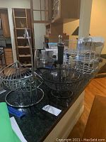 Various metal wire baskets and racks on kitchen counter, along with a sous vide circulator and passive water filtration unit.