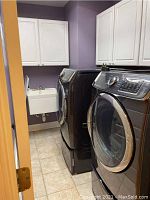 Front and side view showing washer next to dryer under wall cabinets