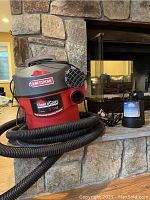 Craftsman Clean N Carry wet/dry vacuum with hose and Superior submersible pump placed on stone fireplace hearth.