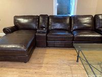 Full view of dark brown leather sectional seating showing chaise, console, sofa and recliner modules