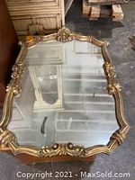 Vintage mirror with gold wooden frame and ornate molded surface detail, measuring about 23.5 x 35 inches.