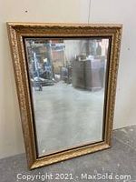 Full view of the large rectangular solid wood framed mirror standing on floor.