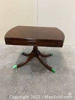 Full view of medium-sized wooden side table with rounded rectangular top and four-legged Duncan Phyfe base with brass feet. Table features a side pull-out wood-framed glass tray with handle, all in mahogany finish.