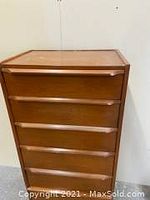 Front view upper half of tall boy dresser showing top surface and curved drawer pulls