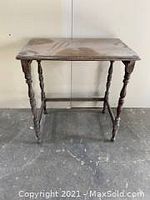 Front view of antique wooden nested table with turned legs and rectangular top.