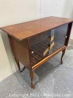Front angle showing wooden cabinet with glass sliding doors and brass handles