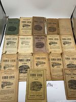 Photo showing all 18 Farmers Almanacs laid out, dates ranging from 1880 to 1919. Aging and wear visible on covers.