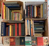 Four boxes filled with assorted books showing titles and collection varieties, including Canadian history, children's books, and dictionaries.