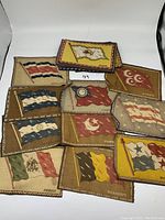 Stack of about a dozen small vintage cloth flags showing various national flags and country names.