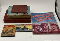 Seven military and navy themed books arranged on a table including Infantry Training 1914 and Favorite Songs of the Red Army and Navy.