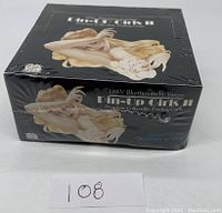 Photo of sealed box with visible 1940s pin-up girl artwork and branding.