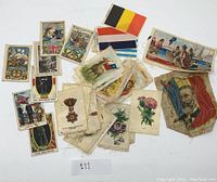 Collection of silk cigarette flags and cards showing various national flags, military themes, and floral designs laid out on a flat surface.