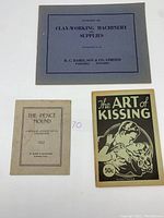 Three vintage booklets laid side by side showing covers: 'The Art of Kissing', 'The Pence Mound 1922', and 'Clay Working Machinery and Supplies' catalog.